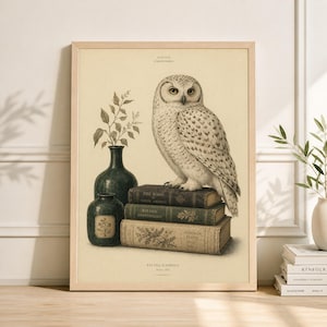 May include: A framed print featuring a detailed illustration of a snowy owl perched atop a stack of antique books. A dark green vase with foliage and a smaller vase are to the left. The print has a vintage aesthetic.