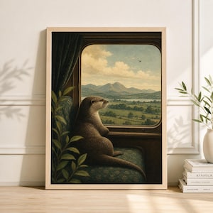 Op de afbeelding: Een ingelijste kunstdruk met een bruine otter die uit een treinraam naar een schilderachtig landschap kijkt. De otter zit op een groen patroonstoeltje, met een donkergroen gordijn zichtbaar. Het landschap omvat bergen, velden en een bewolkte lucht.