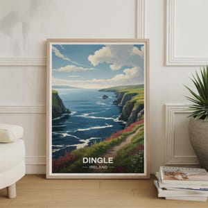 May include: Framed art print featuring a coastal landscape with cliffs, ocean, and a path. The artwork displays a vibrant blue sky with fluffy clouds, green cliffs, and the text "Dingle - Ireland". The print is in a light wood frame.