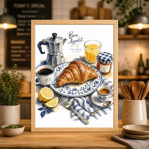 Könnte beinhalten: Ein gerahmter Aquarelldruck einer Frühstücksszene. Er zeigt ein Croissant auf einem blau-weißen Teller, Kaffee, Espresso, Orangensaft und Marmelade. Die Worte "Bon Appétit" und "Café Noir" sind sichtbar.