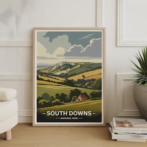 May include: A framed art print depicting the South Downs National Park. The print shows a landscape with green hills, a white cliff, and a red-roofed cottage. The text "SOUTH DOWNS - NATIONAL PARK" is included in the design.