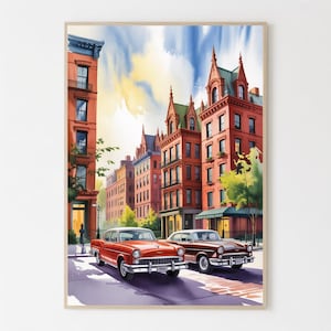 May include: Watercolor print of a city street scene with classic cars. The artwork features red brick buildings, a blue sky, and two vintage cars, one red and one brown. The cars are parked on a cobblestone street.