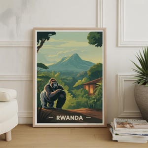 May include: Framed art print featuring a gorilla in a lush, green landscape with a mountain in the background. The artwork has a vintage travel poster style, with the word "RWANDA" at the bottom. The color palette includes greens, blues, and browns.
