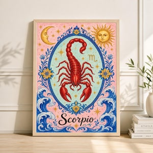May include: A framed art print featuring a red scorpion illustration within an oval frame. The artwork includes a crescent moon, a sun, and the word "Scorpio" in script. The background is pink with blue and yellow floral accents.