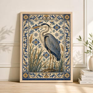 Könnte beinhalten: Gerahmter Kunstdruck mit einem blauen Reiher in einem Sumpf. Der Hintergrund zeigt ein dekoratives Fliesenmuster mit blauen Blumenmotiven auf cremefarbenem Grund. Der Rahmen ist helles Holz.