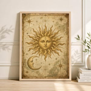 Pode incluir: Uma impressão emoldurada em estilo vintage com um sol com rosto e uma lua crescente. A obra de arte é em tons de ouro e castanho, com detalhes de estrelas. A moldura é de cor de madeira clara.