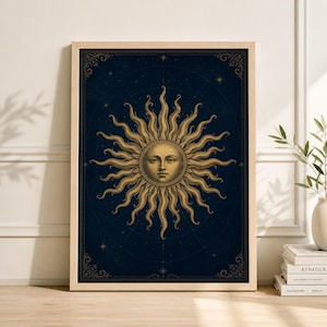 Könnte beinhalten: Gerahmter Kunstdruck mit einer goldenen Sonne mit einem ruhigen Gesicht und strahlenden Flammen vor einem dunkelblauen Hintergrund. Das Kunstwerk hat eine Vintage-Ästhetik mit dekorativen Eckelementen und einem Holzrahmen. Das Sonnendesign erinnert an Tarot- oder astrologische Themen.