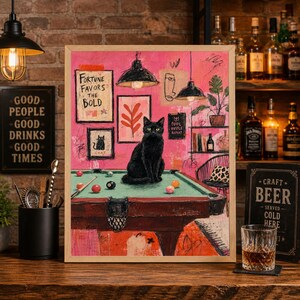 May include: A framed print featuring a black cat on a pool table with billiard balls. The artwork has a pink background with framed art and the text "Fortune Favors the Bold". The print has a vintage, artistic style.