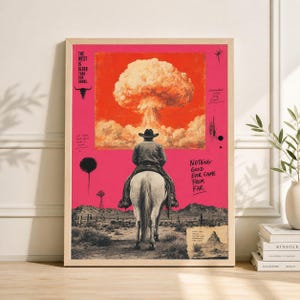 May include: Framed art print featuring a cowboy riding a white horse, set against a pink backdrop with a desert landscape. The artwork includes a mushroom cloud, text that reads "THE WEST IS OLDER THAN OUR BOMBS" and "NOTHING GOOD EVER CAME FROM FAR."