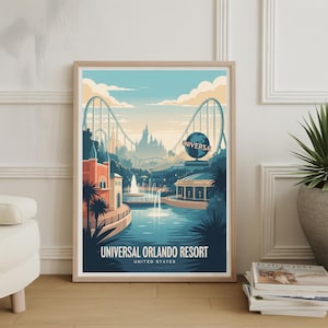May include: Framed art print showing a stylized illustration of Universal Orlando Resort. The artwork features a roller coaster, water features, and buildings in shades of blue, orange, and green. The text "UNIVERSAL ORLANDO RESORT UNITED STATES" is displayed at the bottom.