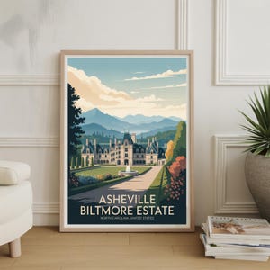 May include: A framed art print featuring the Asheville Biltmore Estate. The artwork depicts the historic mansion with a long pathway, fountain, and manicured gardens. The sky is blue with fluffy clouds, and mountains are in the background. The text "ASHEVILLE BILTMORE ESTATE" is displayed.