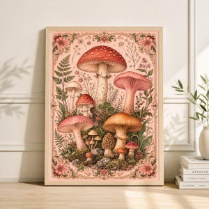May include: A framed art print featuring a watercolor illustration of various mushrooms. The mushrooms are in shades of red, pink, and brown, set against a pink background with floral and botanical accents. The frame is a light wood color.