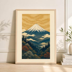 Op de afbeelding: Ingelijste kunstdruk met een berglandschap. Het kunstwerk toont een besneeuwde berg, blauwe heuvels en een bos met herfstbladeren. De lucht is een getextureerde goudkleur. De print zit in een licht houten frame.