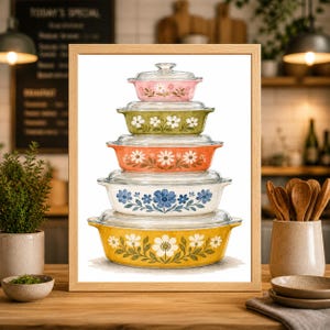May include: A framed print featuring a stack of vintage casserole dishes. The dishes are in various colors, including pink, green, orange, white, and yellow, each adorned with a floral pattern. The print is set against a blurred kitchen background.