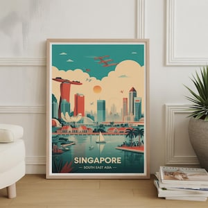 Op de afbeelding: Ingelijste kunstdruk met een gestileerde illustratie van de skyline van Singapore. Het kunstwerk toont iconische bezienswaardigheden in tinten rood, blauwgroen en beige, met de tekst "SINGAPORE - SOUTH EAST ASIA" onderaan. De print zit in een houten lijst.
