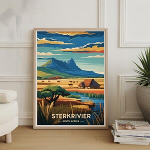 May include: A framed art print showing a vibrant landscape of Sterkrivier, South Africa. The image includes mountains, a river, and a rural scene with a farmhouse and cattle. The sky is a blend of blue, orange, and yellow tones.