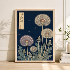 May include: A framed print featuring a botanical illustration of dandelions against a dark blue background. The artwork includes detailed depictions of dandelion seed heads, buds, and leaves, with a Japanese text block in the upper left corner. The frame is a light wood color.