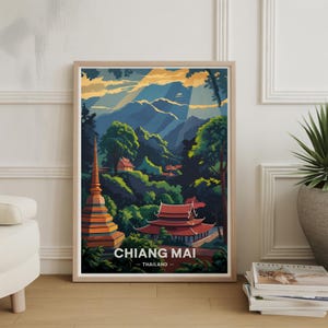 May include: Framed art print featuring a stylized landscape of Chiang Mai, Thailand. The artwork depicts a golden pagoda, red-roofed buildings, lush green trees, and mountains under a sunset sky. The text "CHIANG MAI - THAILAND" is at the bottom.