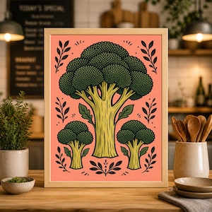 Könnte beinhalten: Gerahmter Kunstdruck mit einer stilisierten Brokkoli-Illustration. Das Kunstwerk zeigt einen großen zentralen Brokkolikopf und zwei kleinere, in Grün und Gelb vor einem korallenfarbenen Hintergrund. Dekorative Blätter und Stiele umgeben den Brokkoli.