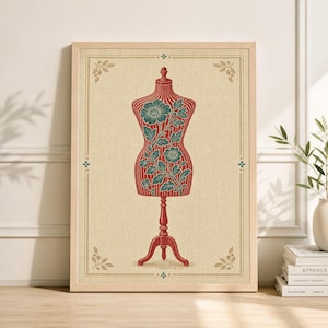 Op de afbeelding: Een ingelijste print met een vintage kleermakersmannequin. Het rode mannequin heeft teal bloemendetails. De achtergrond is lichtbeige met decoratieve hoekaccenten en de lijst is lichtbruin.