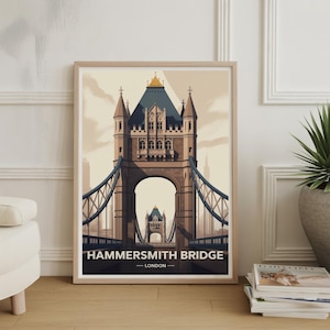 May include: Framed art print featuring Hammersmith Bridge in London. The illustration depicts the bridge in a stylized, vintage aesthetic, with a muted color palette of beige, blue, and brown. The text "HAMMERSMITH BRIDGE - LONDON" is displayed at the bottom.