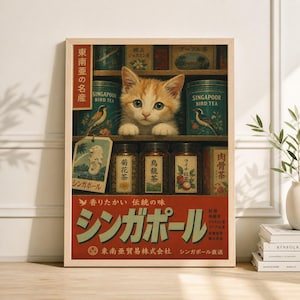 May include: A framed vintage-style poster featuring a ginger kitten peering out from behind shelves of tea tins and jars. The poster has Japanese text and illustrations of birds and tea leaves, with the words "Singapore Bird Tea" visible.