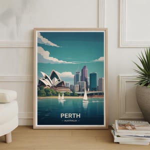 May include: A framed art print featuring a stylized illustration of Perth, Australia. The artwork depicts the city skyline, including the iconic Opera House, with sailboats on the water. The print has a light wood frame and the text "PERTH - AUSTRALIA".