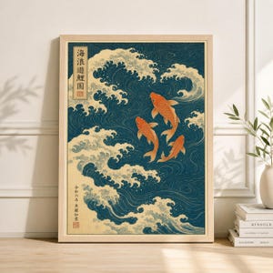 May include: Framed art print featuring three orange koi fish swimming in a sea of blue waves. The artwork has a traditional Japanese aesthetic, with text in the upper left corner and lower left corner. The print is in a light wood frame.