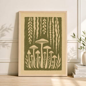 May include: A framed art print featuring a stylized illustration of mushrooms in shades of green and cream. The artwork includes various mushroom shapes and hanging plant-like elements, set against a textured background. The print is in a light wood frame.