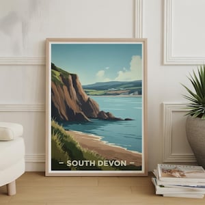 May include: A framed art print featuring a coastal landscape with a beach, cliffs, and ocean. The artwork has a vintage travel poster style, with the text "SOUTH DEVON" at the bottom. The color palette includes shades of blue, brown, green, and beige.