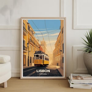 May include: Framed art print featuring a yellow tram traveling down a street in Lisbon, Portugal. The artwork has a vintage travel poster style, with buildings in shades of yellow and orange. The text "LISBON - PORTUGAL" is at the bottom.