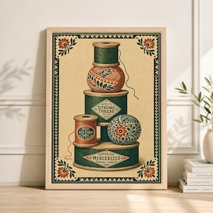May include: A framed print featuring a vintage illustration of spools of thread. The spools are stacked, with green and orange thread. The print has a beige background and a decorative border with floral accents. The text on the spools reads "Quality Strong Thread" and "Superior Mercerized Sewing Thread."