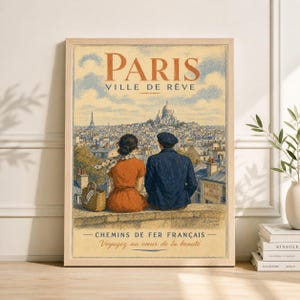 May include: A framed vintage travel poster of Paris, France. The poster features a couple overlooking the city, with the Eiffel Tower and Sacré-Cœur Basilica visible. Text includes "PARIS VILLE DE RÊVE" and "CHEMINS DE FER FRANÇAIS".