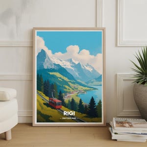 May include: Framed art print featuring a scenic view of Rigi, Switzerland. The artwork depicts a red cable car ascending a mountain, with a lake and snow-capped mountains in the background. The sky is blue with fluffy white clouds. The text "RIGI - SWITZERLAND" is at the bottom.