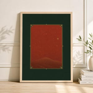 May include: A framed art print featuring a red and dark green landscape. The artwork depicts a desert scene with a starry sky and a decorative gold border. The frame is a light wood color.