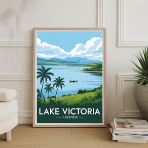 May include: Framed art print featuring a scenic view of Lake Victoria in Uganda. The artwork depicts a serene lake scene with palm trees, a small boat, and rolling green hills under a blue sky with fluffy clouds. The text "LAKE VICTORIA UGANDA" is displayed at the bottom.