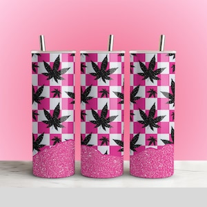 May include: Three stainless steel tumblers with a pink and white checkered pattern and black cannabis leaf designs. The bottom of each tumbler has a band of pink glitter. Each tumbler has a silver straw.