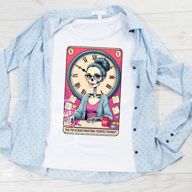 May include: White t-shirt featuring a cartoon illustration of a skeleton woman with glasses, a clock face, and the text "The Procrastinating Perfectionist." The woman is wearing a pink top and blue cardigan. A light blue button-down shirt is draped over the t-shirt.