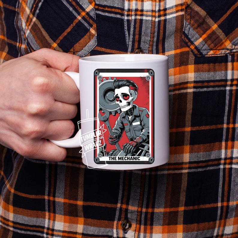 May include: White ceramic mug featuring a stylized illustration of a skeleton mechanic holding a wrench and gear. The design includes a red background and the text "THE MECHANIC". The mug has a white handle.