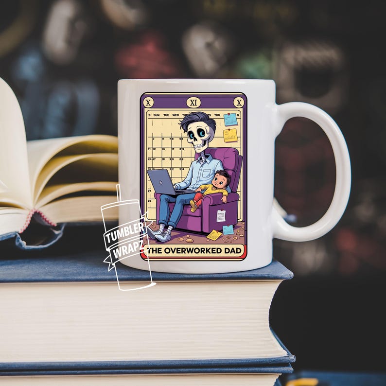 May include: White ceramic mug featuring a colorful illustration of a skeleton working on a laptop with a child. The design includes a calendar and the text "THE OVERWORKED DAD". The mug has a large handle and is sitting on a stack of books.