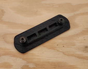 May include: A black plastic 3D printed part with five slots and two screw holes.