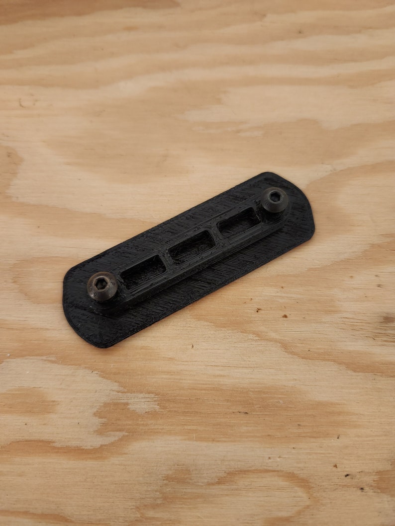 May include: A black plastic 3D printed part with five slots and two screw holes.