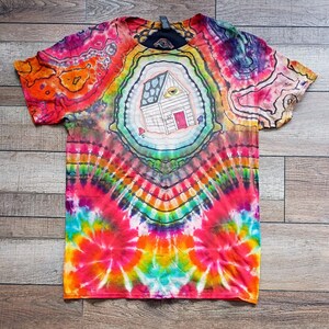 May include: A vibrant tie-dye t-shirt with a psychedelic design. The shirt features a central illustration of a house with an eye, surrounded by colorful patterns in shades of orange, pink, blue, and green. The shirt is a short-sleeved crew neck.
