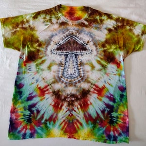 May include: A tie-dye t-shirt with a mushroom design in the center. The shirt is a blend of green, yellow, red, blue, and purple colors.
