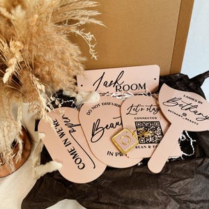May include: A set of pink acrylic signs with black lettering. The signs include the text "Lash Room", "Do Not Disturb", "Beauty", "Let's Stay Connected", "Come In We're Open", and "Lashes by Bethany Beauty".