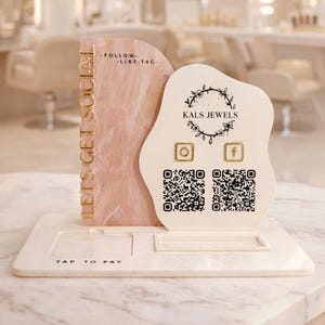 May include: A white and pink display stand with the text "LET'S GET SOCIAL" and "TAP TO PAY". The stand features the brand name "KALS JEWELS", social media icons, and QR codes for online engagement.