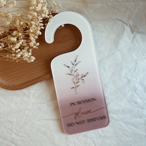 May include: White and pink door hanger with a floral design and the text "IN SESSION Please DO NOT DISTURB".