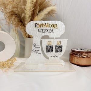 May include: A decorative white acrylic stand with the text "Tori Moon" and "LET'S STAY CONNECTED". The stand has a mixer design with QR codes and the words "SCAN ME!". It also includes the phrase "Life is sweet, Enjoy a treat".