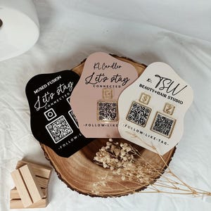 May include: Three black, pink, and white signs with the text "Let's stay connected" and QR codes. The signs are shaped like a cloud and have gold accents.