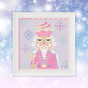 May include: A pink and white nutcracker with a cupcake hat and a candy cane in his hand. The background is a light purple with snowflakes.